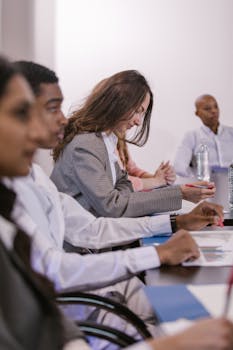 A diverse group of professionals engaged in a focused and attentive business meeting in a conference room.