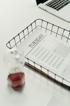A minimalist workspace featuring a planner, hourglass, and laptop for effective scheduling.