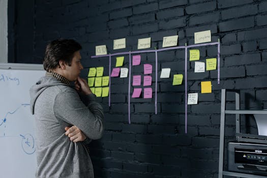 Adult male focusing on task planning using sticky notes on a black wall in a contemporary office setting.