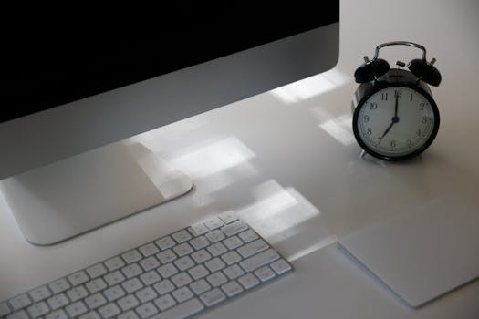 Elevate productivity with a sleek workspace featuring a computer, keyboard, and analogue clock.
