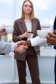 Professionals networking over coffee, exchanging handshakes in a business setting.
